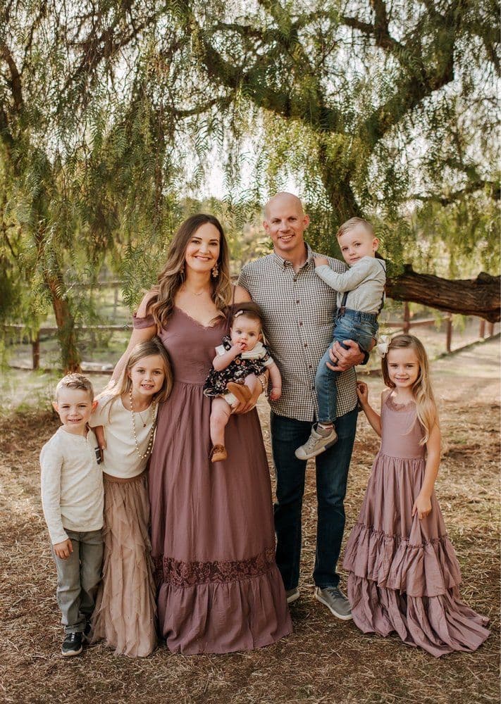 A father and mother posing with five kids under a tree