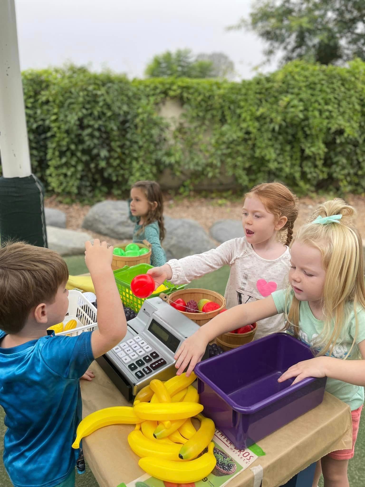 Four children playing with a cash register toy