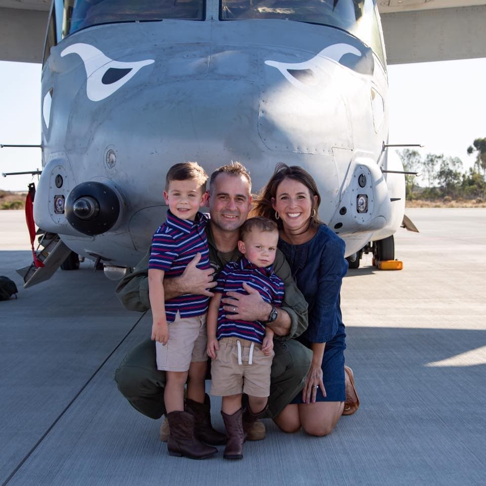 A four person family posing in front of an airplane